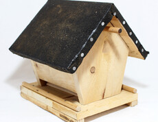 Ein Futterhäuschen für Vögel aus Holz.